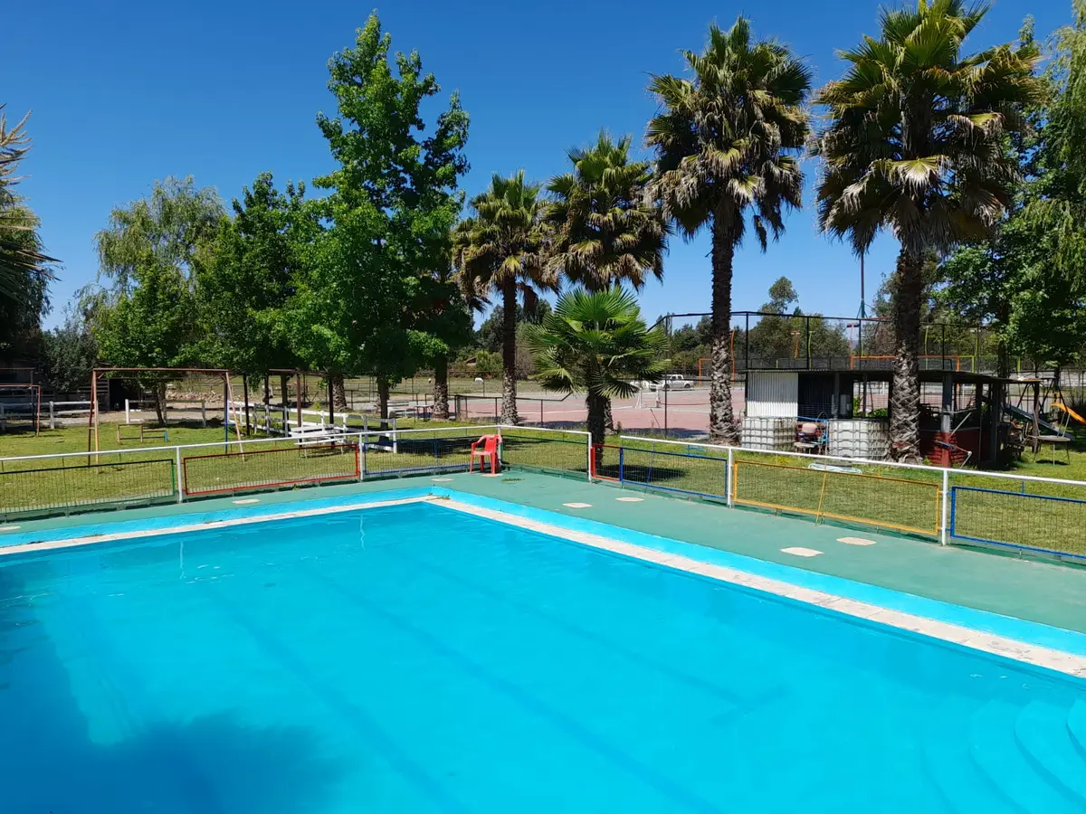 Piscina de Rancho Itahue rodeada de césped, palmeras y jardines