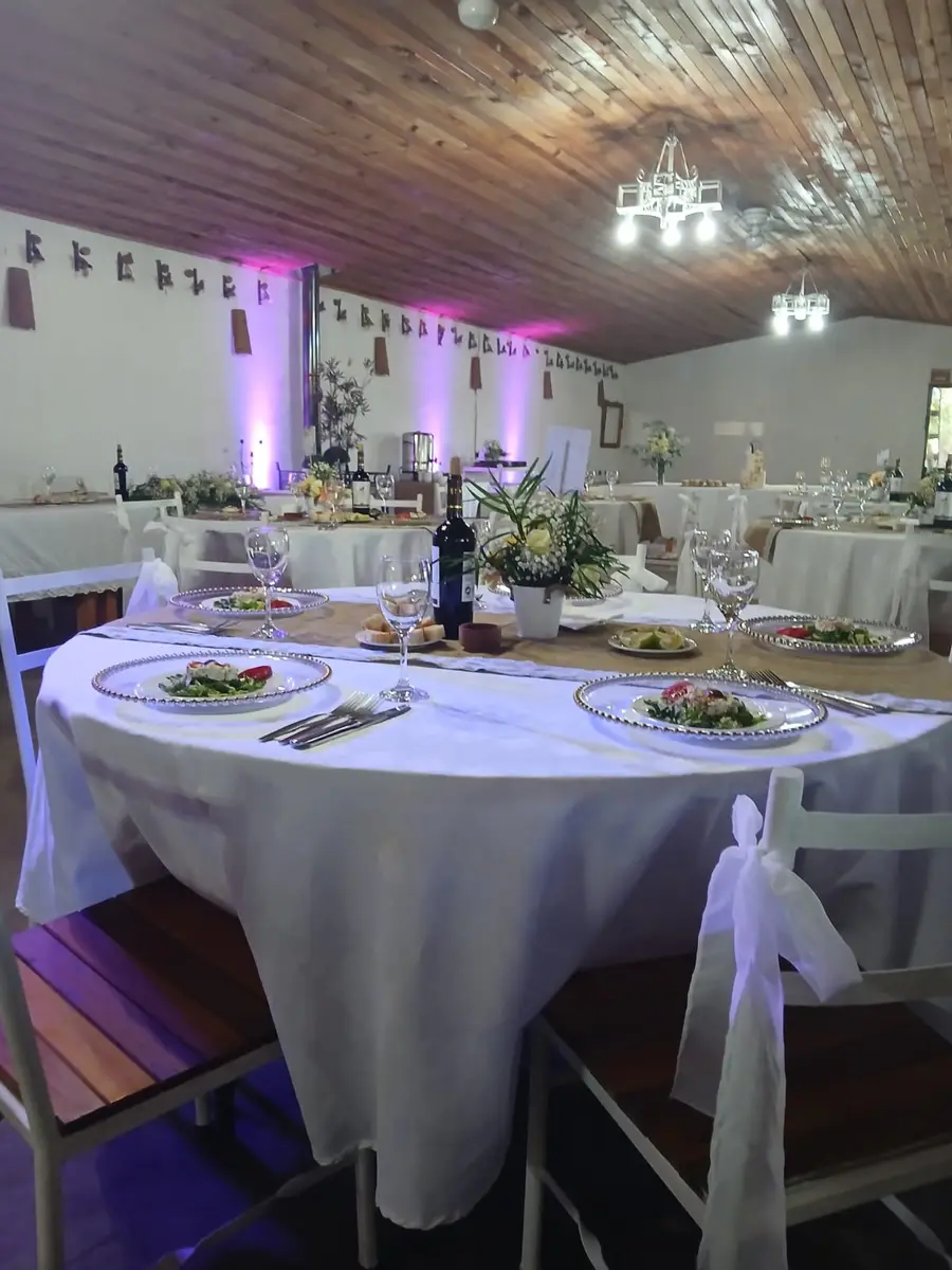 Mesa redonda con mantel blanco, centro floral y platos servidos