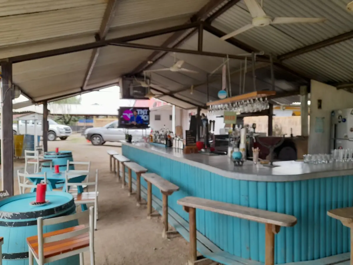 Barra azul del quincho techado con mesas y televisor