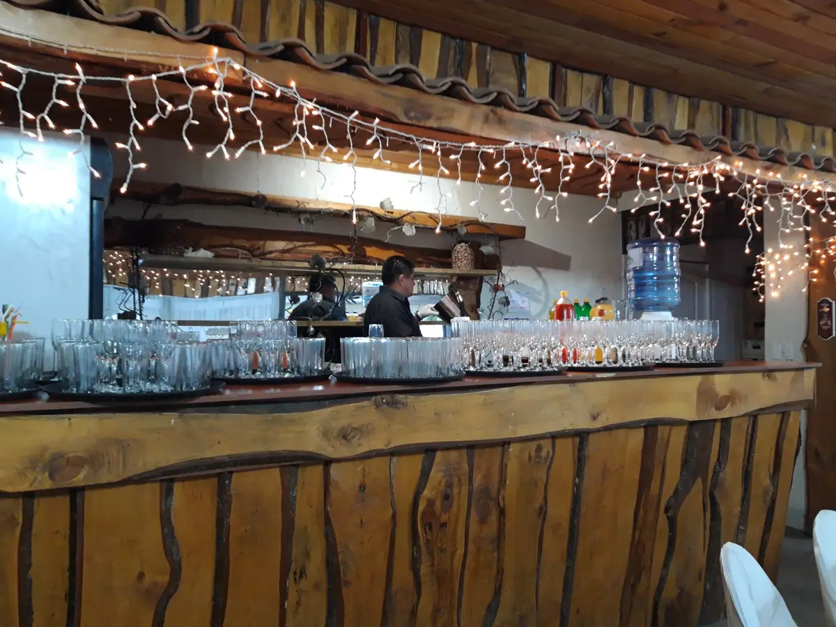 Barra de madera del quincho con vasos y luces