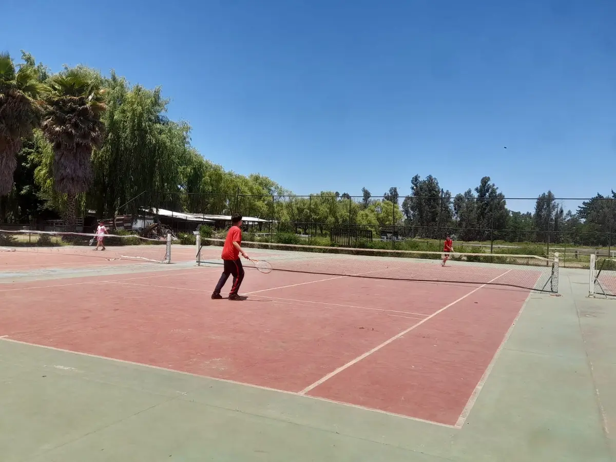 Personas jugando en la cancha de tenis al aire libre