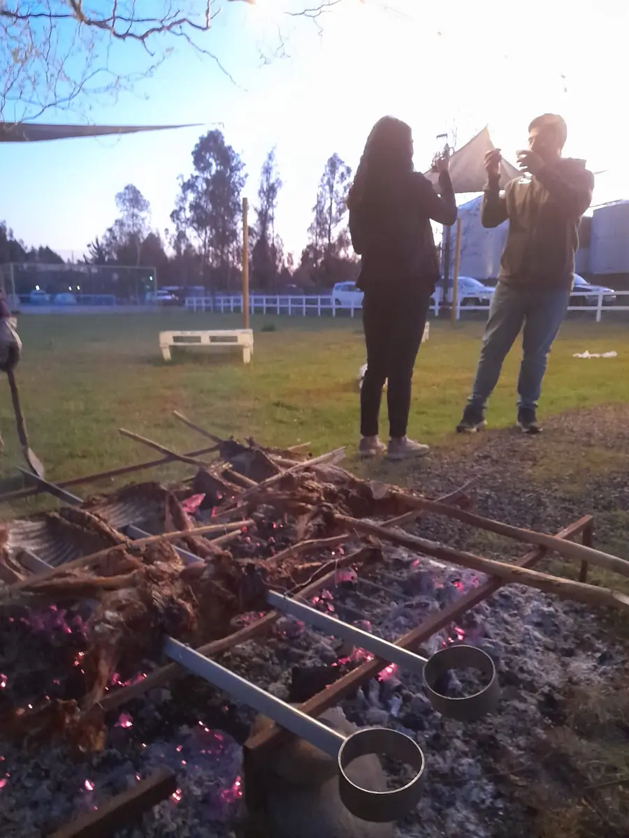 Asado a las brasas con personas junto a la parrilla