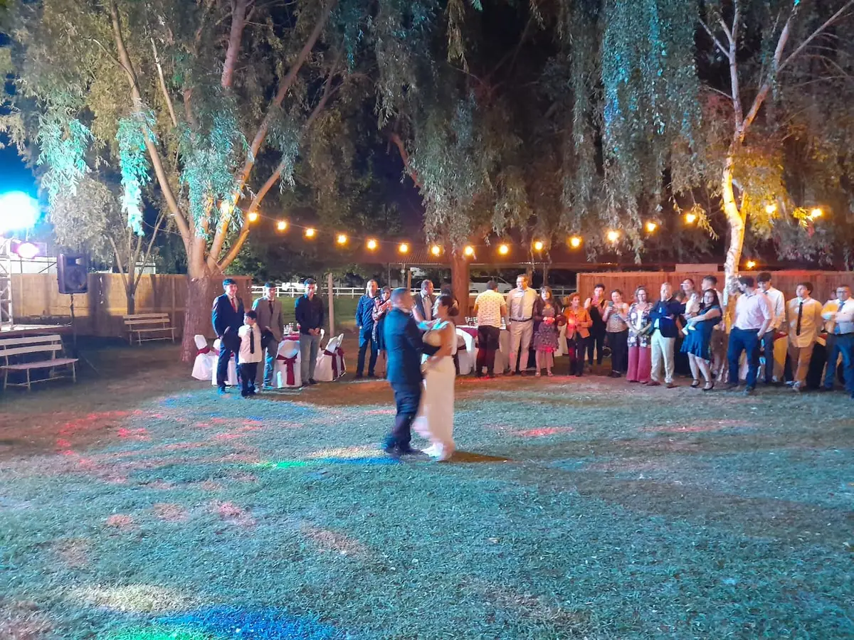 Novios bailando en el césped bajo guirnaldas de luces